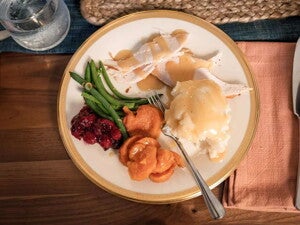 Un plato que contiene vegetales, pure de papa y pollo