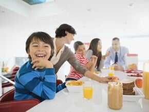 Familia desayunando juntos en la cocina, sentados alrededor de la mesa.