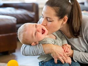 Madre dando beso en la mejilla al bebe