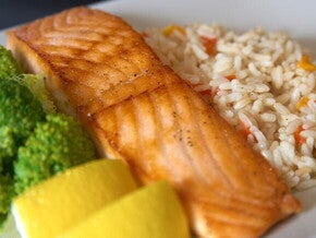 Plato con salmón a la parrilla, arroz con verduras, brócoli y rodajas de limón