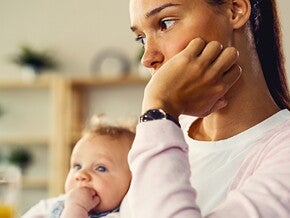 Mujer con depresión posparto sentada con su bebé, triste. 