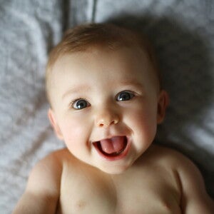 Bebé de 6 meses acostado en la cama sonriendo.