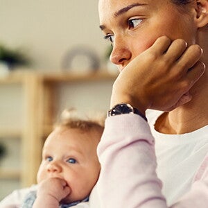 Mujer con depresión posparto sentada con su bebé, triste. 