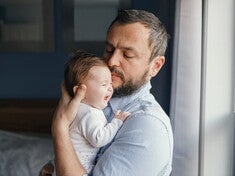 Papá sosteniendo a bebé llorando para ayudarle a eructar