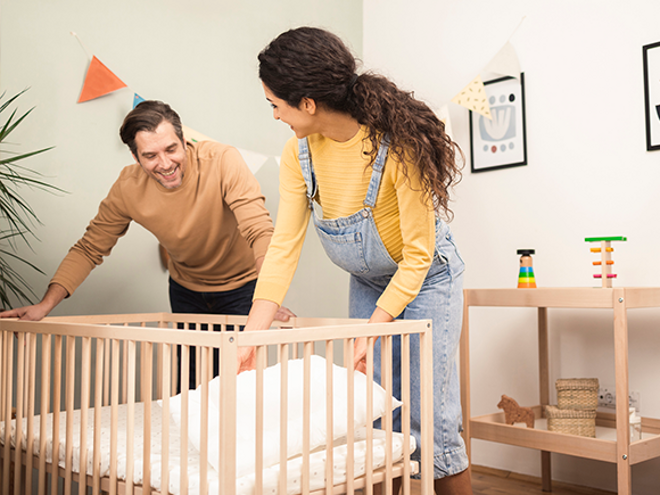 Preparate para la llegada de tu bebé con nuestra guía completa Un hombre y una mujer preparan la cuna del bebe
