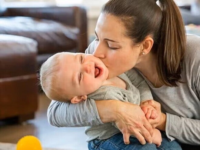 Madre dando beso en la mejilla al bebe