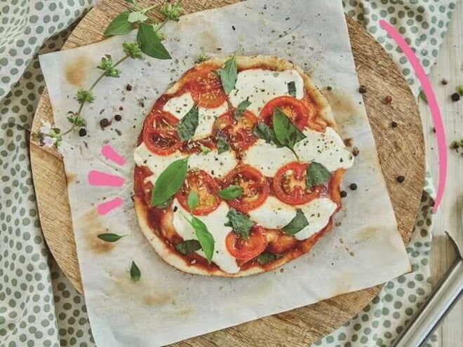 Pizza margarita Pizza margarita en el centro con decoración de queso y albahaca alrededor