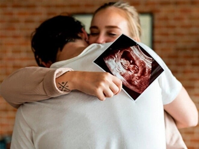 Identificar los síntomas de embarazo a tiempo es importante para prevenir riesgos Pareja abrazándose mientras la mujer sostiene una ecografía