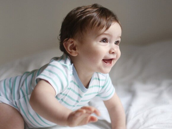 Bebé de 6 meses gateando sobre la cama.