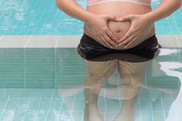 Natación para embarazadas mujer embarazada en la piscina sosteniendo su panza