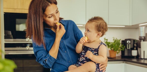 Mamá con su hija comiendo alimentos para evitar los tipos de alergias en bebés Mamá con su hija comiendo alimentos para evitar los tipos de alergias en bebés