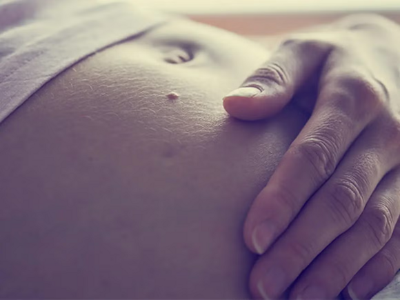 Mujer embarazada en el segundo trimestre acariciando su vientre.